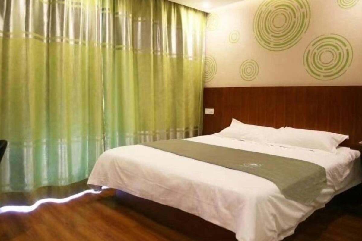 A hotel room with a large bed, a wooden headboard, and a wall with circular patterns.