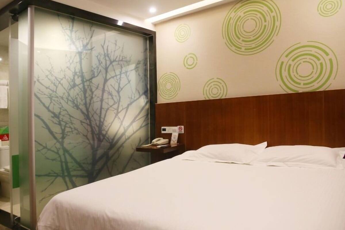 A hotel room with a bed, a nightstand, a phone, and a wall with circular patterns.