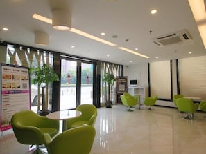A modern lobby with green chairs, a reception desk, and a large window with blinds. - GreenTree Inn Shanghai Hotel (Shanghai)