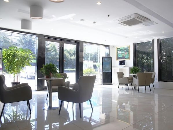 A spacious lobby with a modern design, featuring a large reception desk, several seating areas, and large windows offering views of the outdoors. - GreenTree Inn Shanghai Hotel (Shanghai)