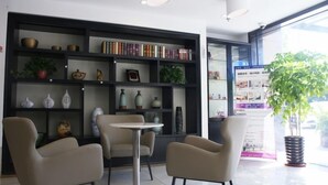 A modern interior with a round table and two chairs, a bookshelf with various decorative items, and a large window with a view of the outside. - GreenTree Inn Shanghai Hotel (Shanghai)