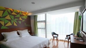 A hotel room with a large bed, a desk, two chairs, and a view of the city through large windows. - GreenTree Inn Shanghai Hotel (Shanghai)