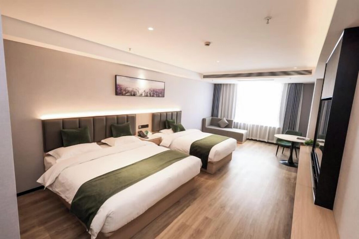 A hotel room with two beds, a desk, and a chair.