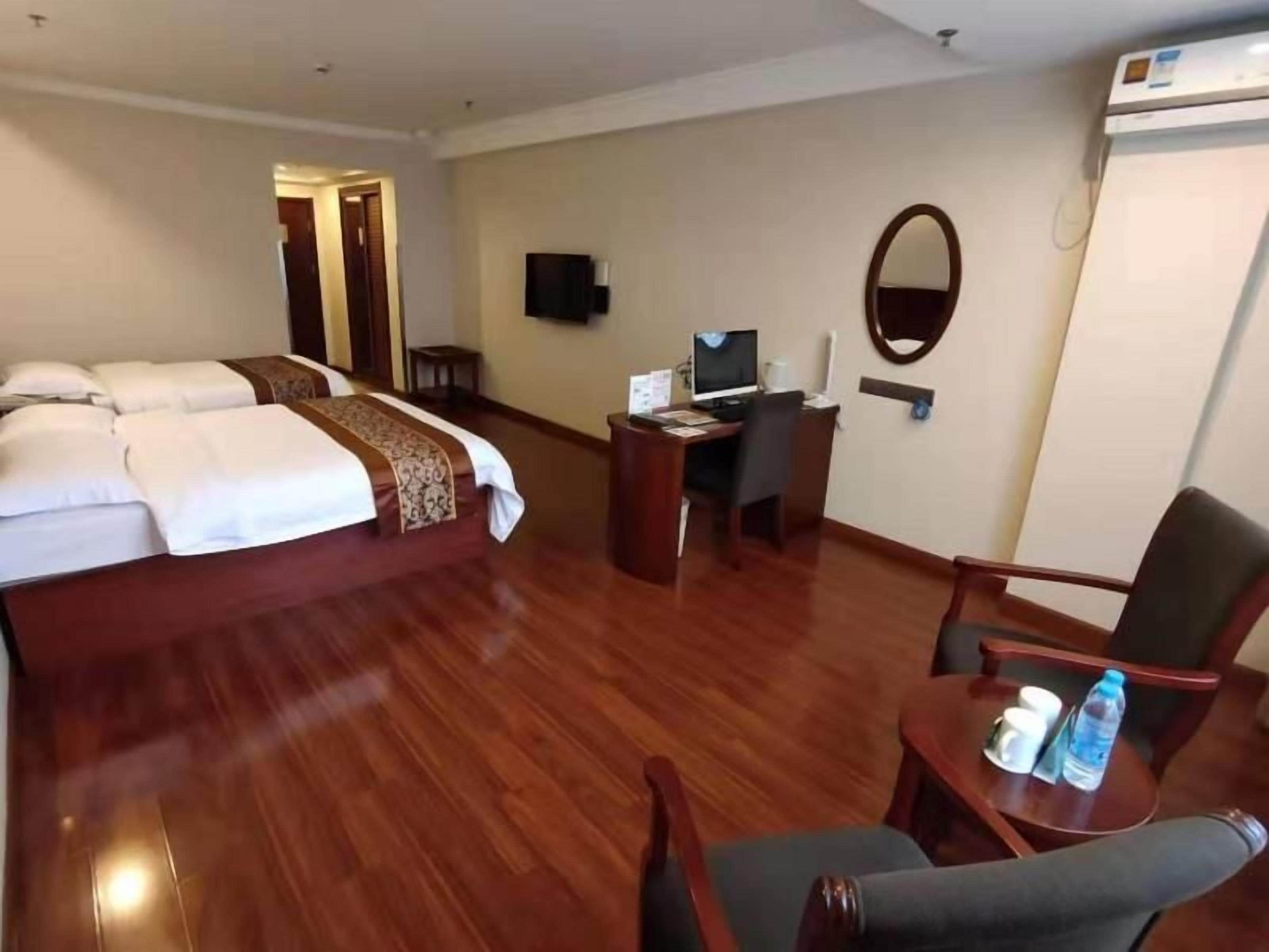 A hotel room with a bed, desk, chair, and a television.
