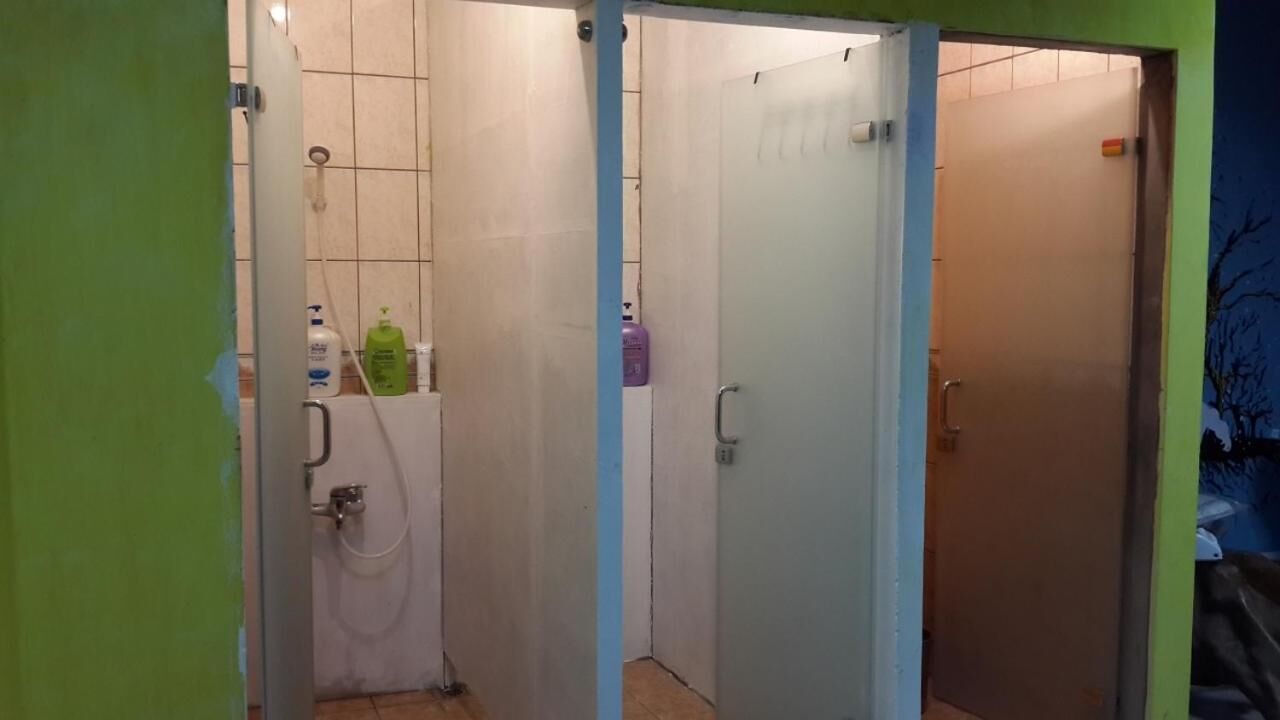 Un baño con inodoro, lavamanos y dos puertas. Hay artículos de aseo en la encimera.