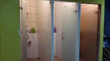 Un baño con inodoro, lavamanos y dos puertas. Hay artículos de aseo en la encimera.