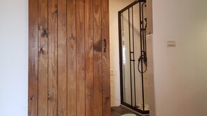 A wooden sliding door leading to a shower area with a glass door and a small green mat on the floor. - Taroko Susi Space (Xincheng)