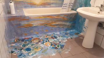 A bathroom with a bathtub, a sink, and a tiled floor with a painted design.
