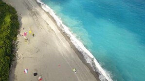 A beach with clear turquoise waters, a sandy shore, and lush green hills in the background. - Taroko Susi Space (Xincheng)