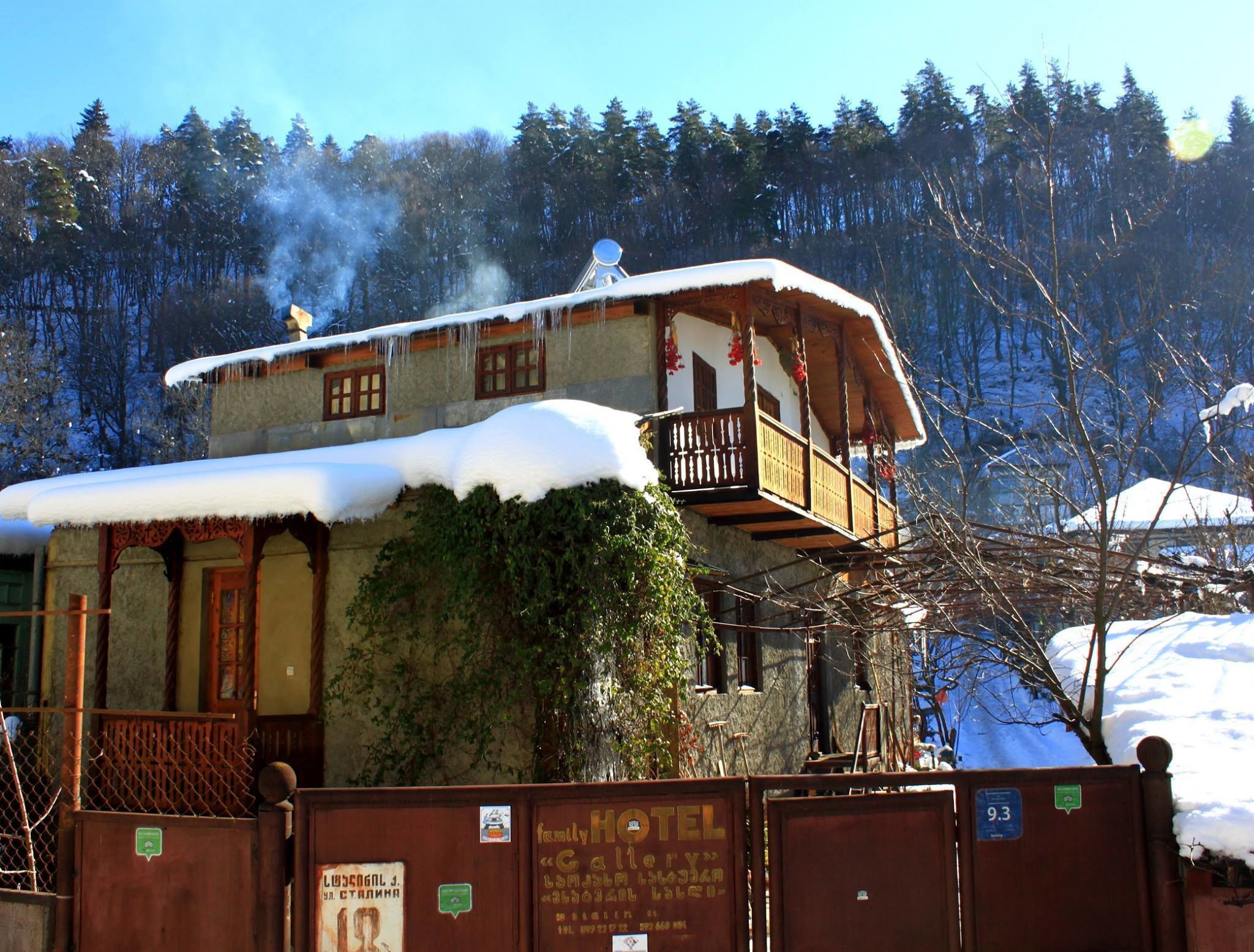Un edificio de dos pisos con un balcón, rodeado de árboles cubiertos de nieve.