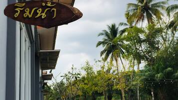 A building with a hanging sign, a pathway, and palm trees in the background.