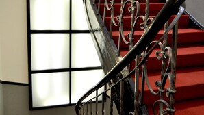 A staircase with ornate metal railings and red carpeted steps.