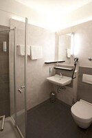 A modern bathroom with a glass shower enclosure, a sink with a mirror, and a toilet.