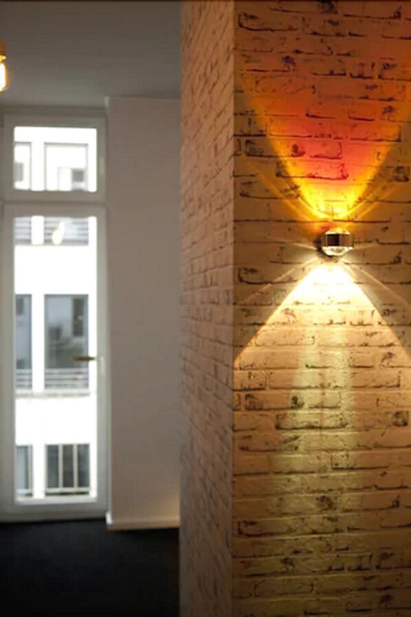 A hallway with a brick wall and a door leading to a bright room. - Hotel Cristall (Frankfurt)