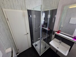 Un bagno moderno con doccia vetrata, lavandino bianco e specchio sopra il lavandino.