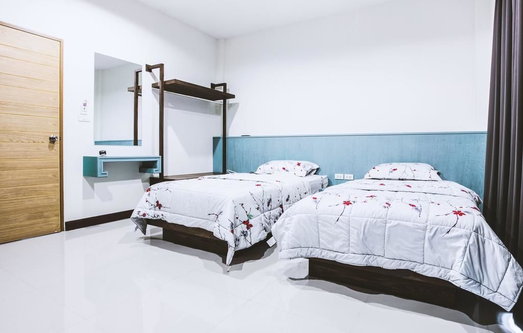 Een slaapkamer met twee bedden, een houten deur, een spiegel en een blauwe accentmuur.