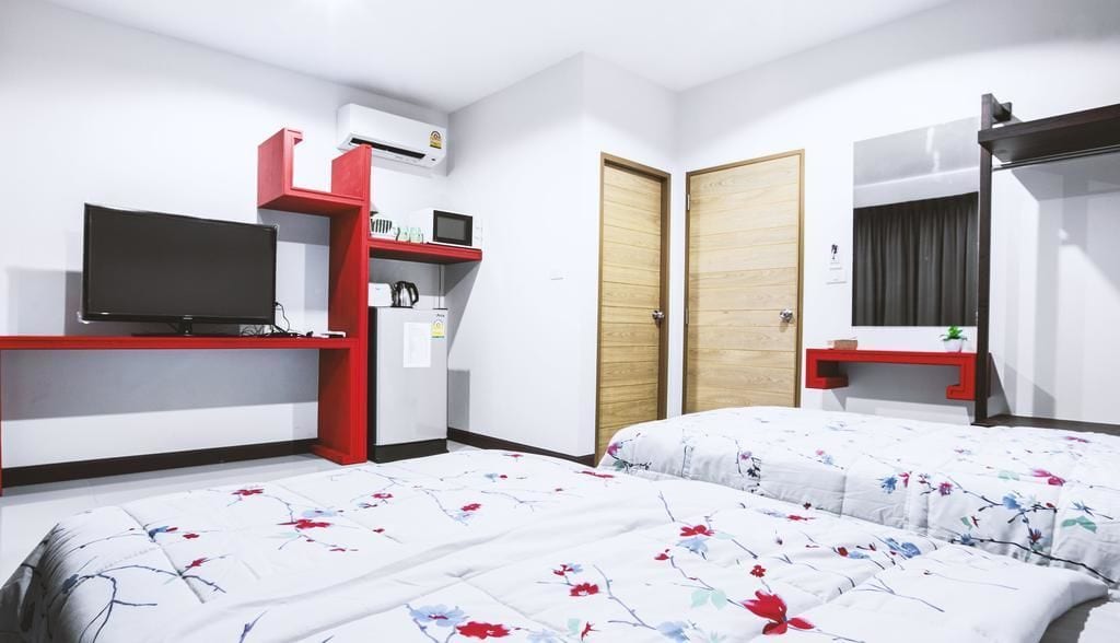 A hotel room with a bed, a TV, a desk with a computer, and a wardrobe.
