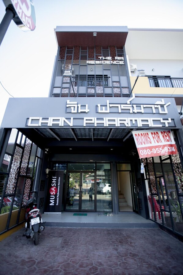 A building with a sign for 'Chan Pharmacy' and a 'Rooms for Rent' sign. - Ra Residence Phuket (Chalong)
