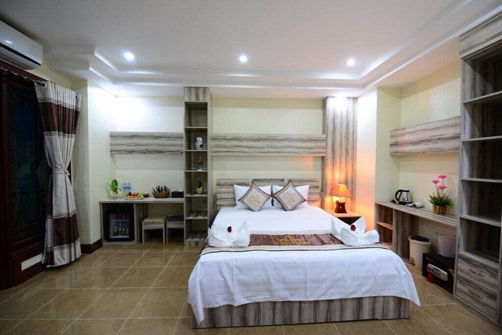 Una camera da letto ben illuminata con un letto grande, comodini, un armadio e uno scaffale con oggetti decorativi.