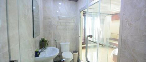 Un baño moderno con cabina de ducha de vidrio, lavabo e inodoro.