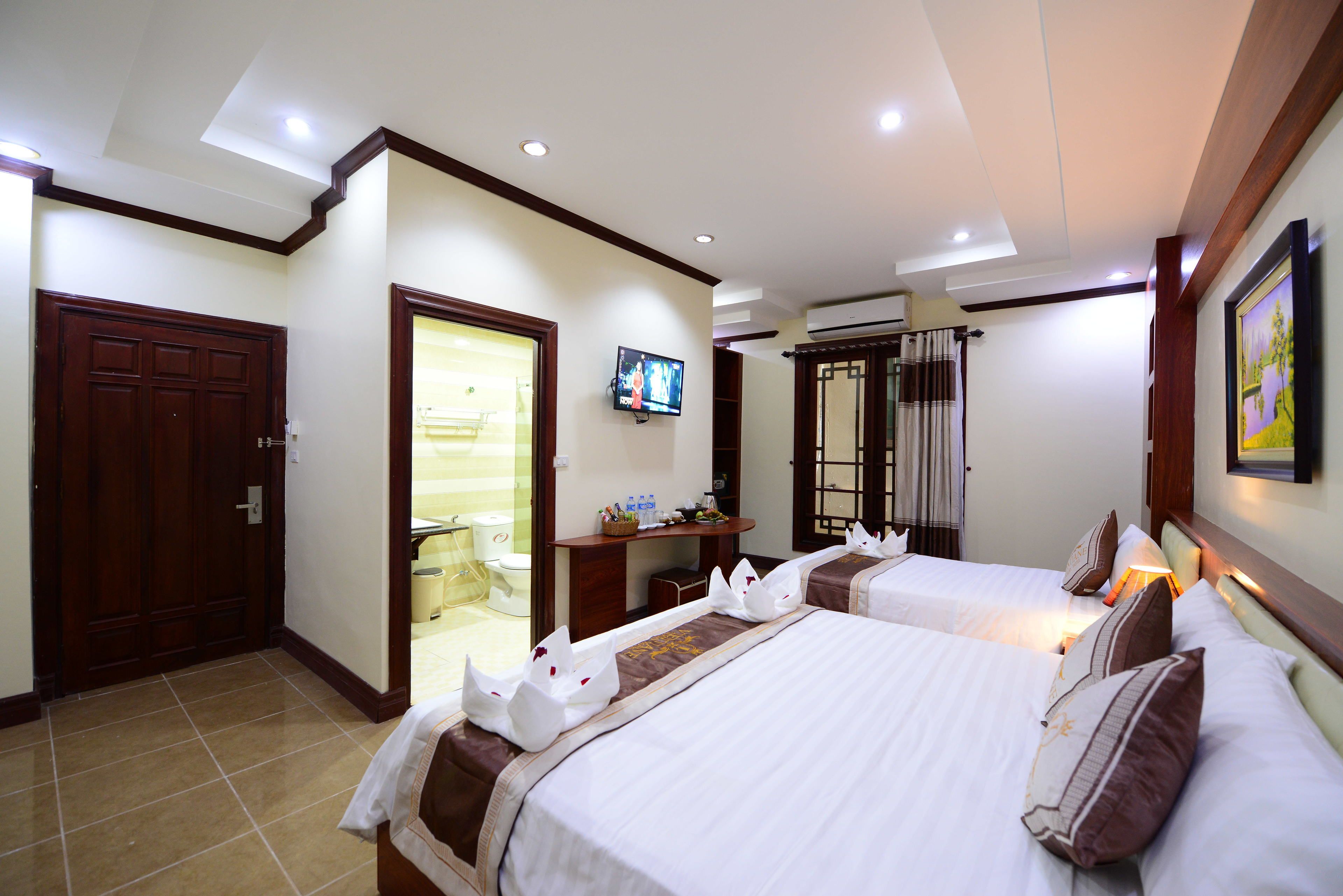 A hotel room with two beds, a television, a desk, and a wardrobe.