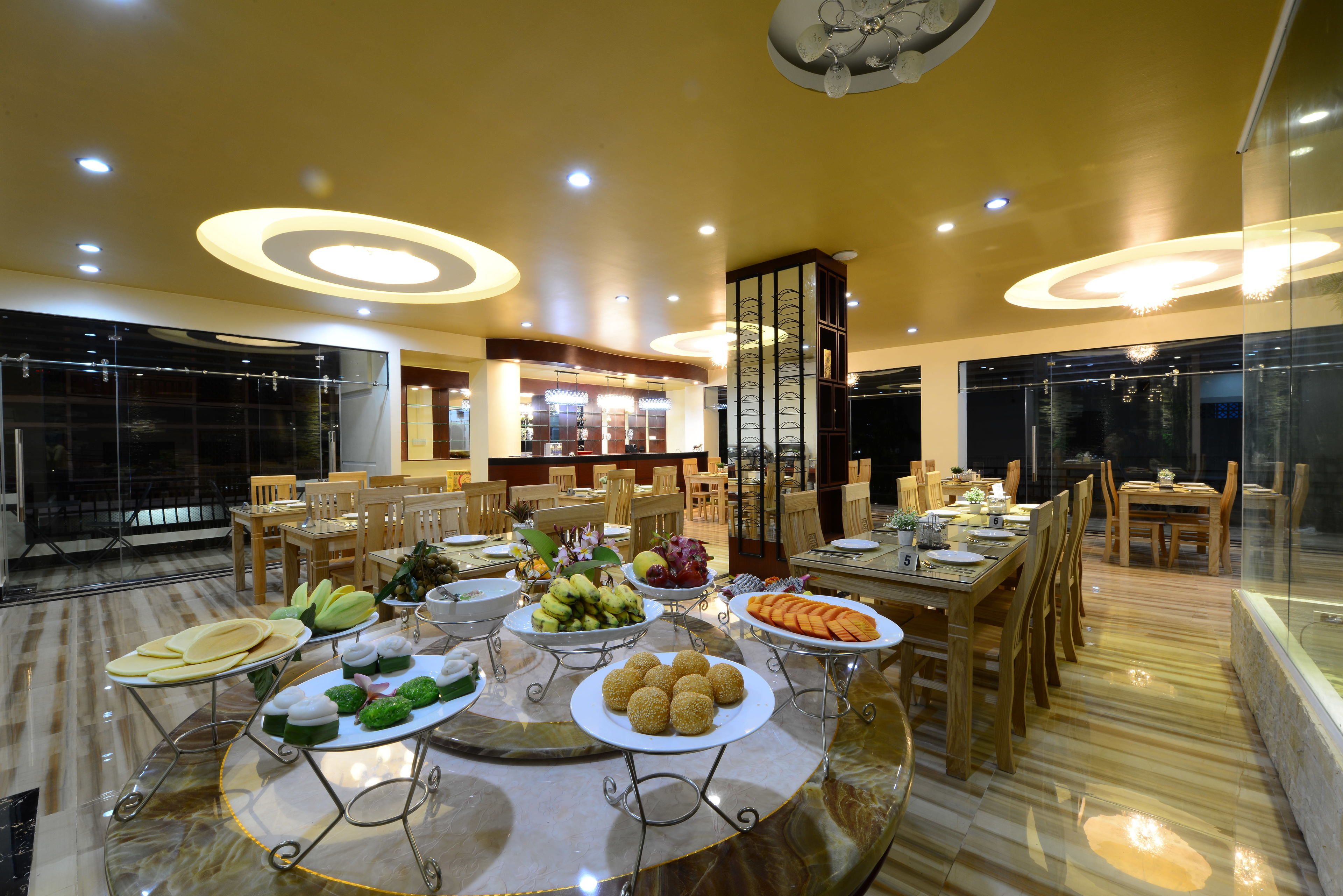 A dining area with a marble table, wooden chairs, and various food platters.