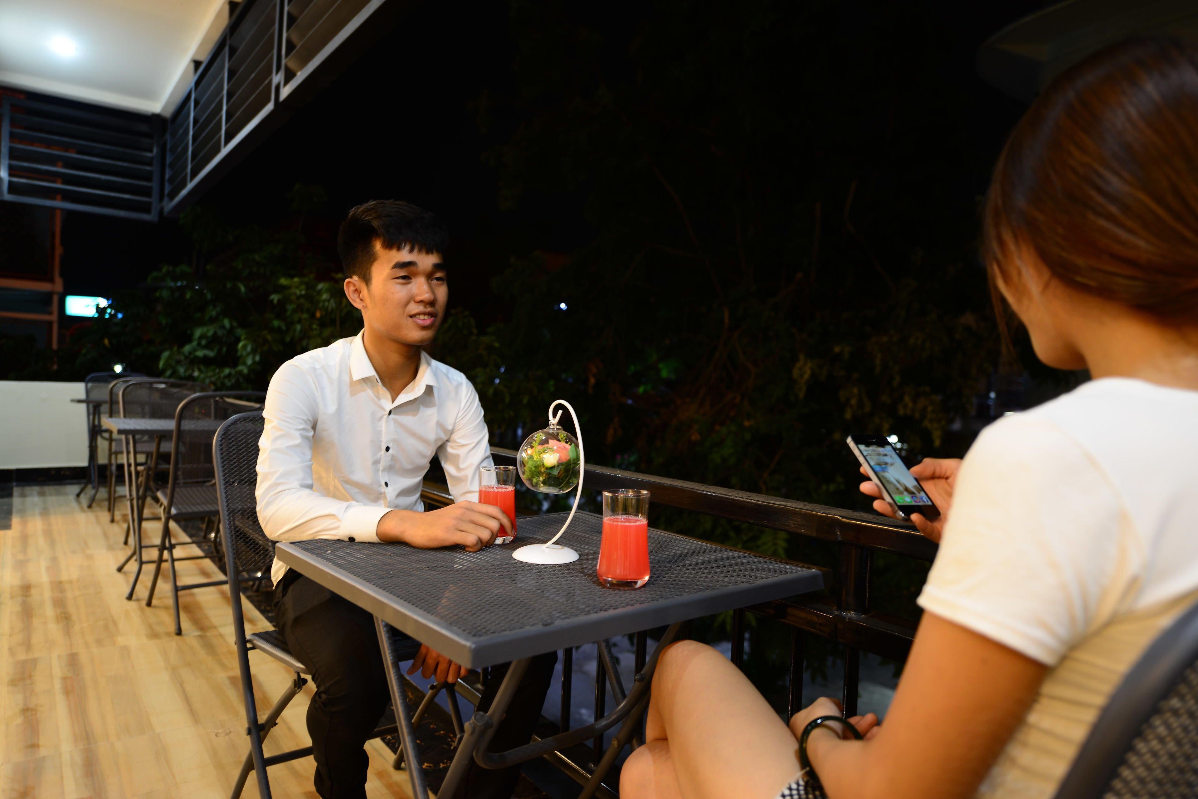 Um homem e uma mulher sentados numa mesa ao ar livre, com bebidas e um globo.