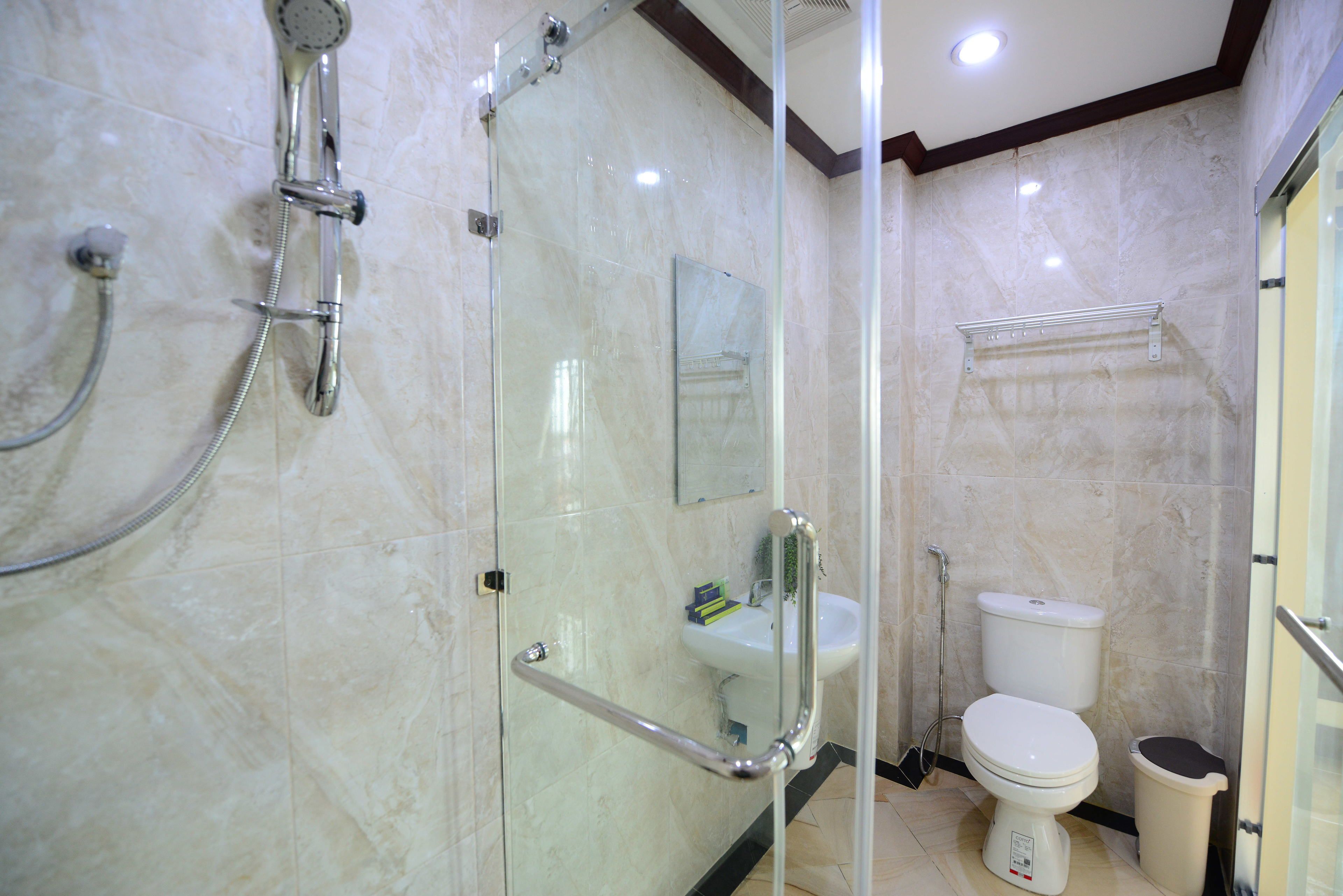 A modern bathroom with a glass-enclosed shower, a white sink, and a toilet.