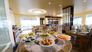 Un tavolo da buffet con diversi cibi e una sala da pranzo con tavoli e sedie.