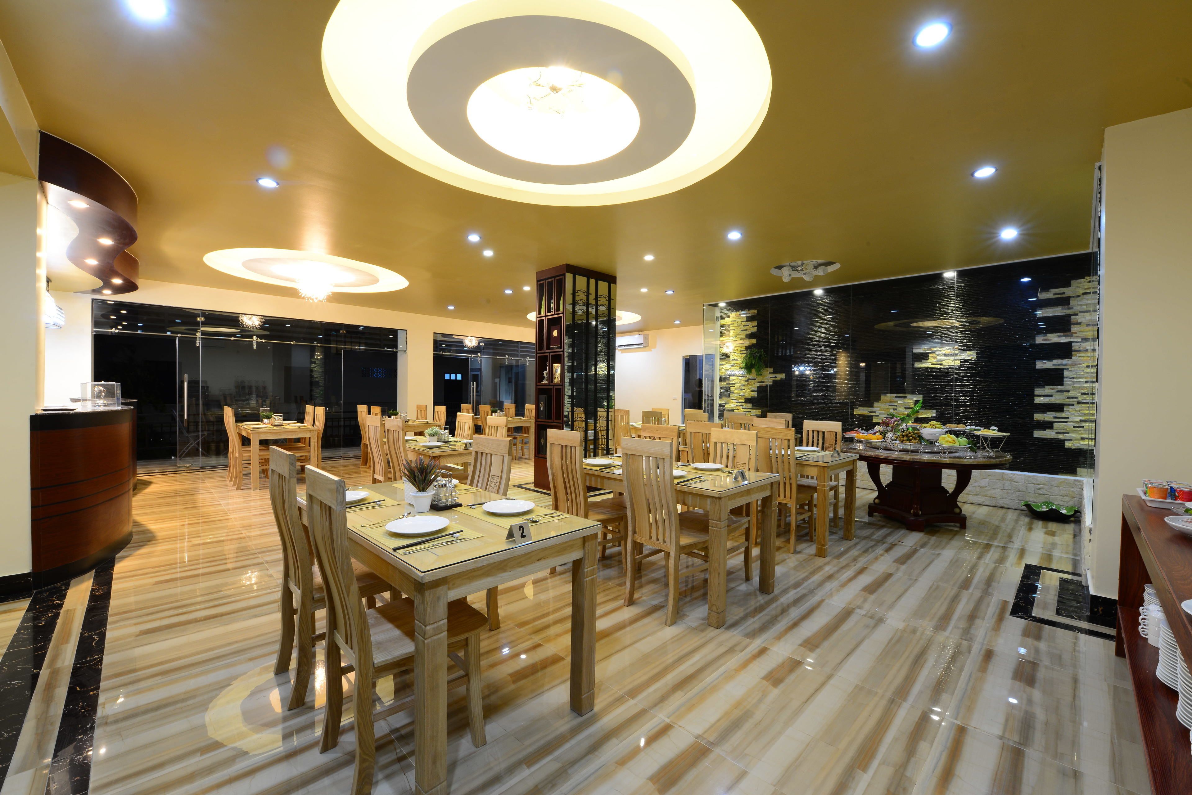 Un amplio comedor con varias mesas y sillas, un columnario decorativo central y un diseño de techo moderno.