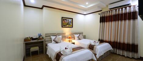 A hotel room with two beds, a nightstand with a lamp, a painting on the wall, and a window with curtains.