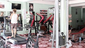 Et fitnesscenter med løbebånd, styrkemaskiner og spejlvæg.