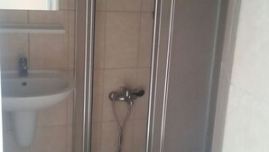 Une salle de bain avec une douche à parois de verre, un lavabo et un miroir.