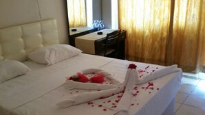 Une chambre d’hôtel avec un lit bien fait, un bureau et une chaise.
