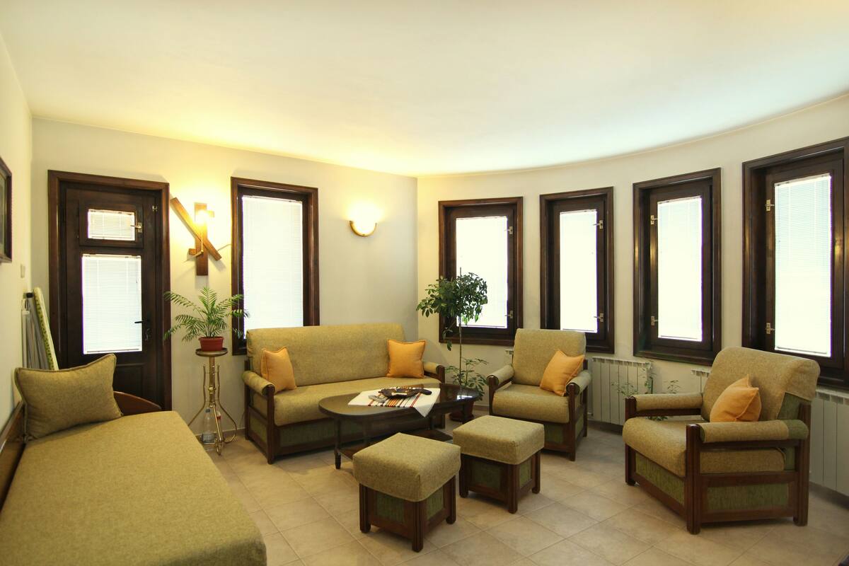 A living room with a sofa, armchairs, a coffee table, and a potted plant.