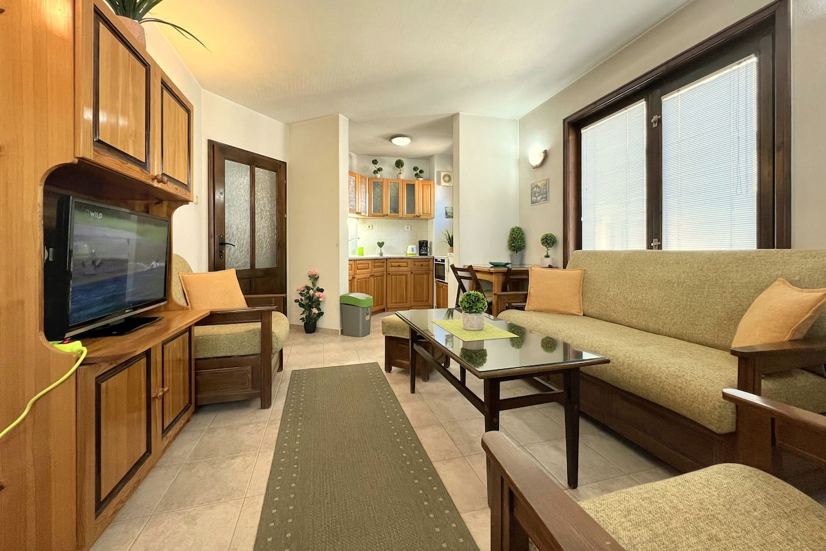 A living room with a TV, sofa, coffee table, and wooden cabinets.