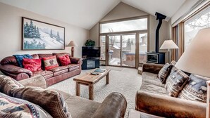 A cozy living room with a brown leather sofa, a wooden coffee table, and a television.
