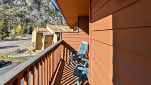 A wooden cabin with a balcony, a blue chair, and a view of a mountain and forest. - Cedar Lodge  309 Studio Bedroom Condo by RedAwning (Frisco)