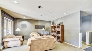 A living room with a beige sofa, a wooden bookshelf, and a lamp. - Cedar Lodge  309 Studio Bedroom Condo by RedAwning (Frisco)