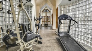 Un gimnasio con equipo de ejercicio, cinta de correr y pared de espejos.