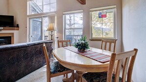 A dining area with a wooden table, chairs, and a potted plant. There is a fireplace and a television in the background. - Tarn Landing  #c-4 2 Bedroom Condo by RedAwning (Frisco)