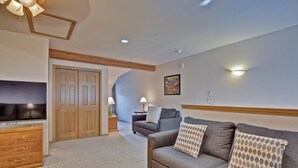 A modern living room with a grey sofa, wooden furniture, and a TV. - Tarn Landing  #c-4 2 Bedroom Condo by RedAwning (Frisco)