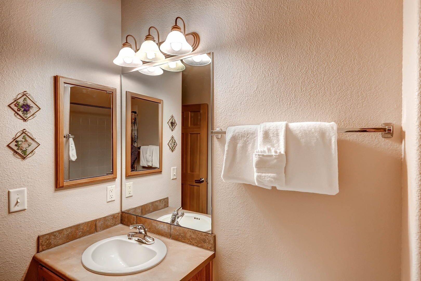 A bathroom with a sink, mirror, and three light fixtures above it.