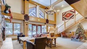 A spacious lobby with a high ceiling, wooden beams, a staircase, and a Christmas tree. - Copper Springs  209 2 Bedroom Condo by RedAwning (Copper Mountain)