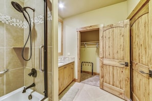 A bathroom with a shower, a bathtub, wooden cabinets, and a mirror.