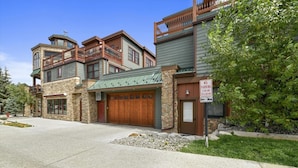 A multi-story building with a stone facade, large wooden garage doors, and a balcony. - S Off Main  #4 2 Bedroom Condo by RedAwning (Frisco)