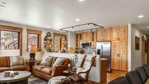 A modern living room with a brown leather sofa, a round coffee table, and a wooden rocking chair. - Mount Victoria Lodge #d 3 Bedroom Condo by RedAwning (Frisco)