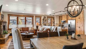 A spacious living room with a fireplace, a dining area with a wooden table, and a kitchen with wooden cabinets and a stainless steel refrigerator. - Mount Victoria Lodge #d 3 Bedroom Condo by RedAwning (Frisco)