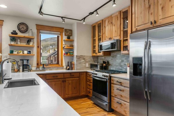 Una cocina moderna con armarios de madera, electrodomésticos de acero inoxidable, una isla grande y un ventanal con vistas al exterior.