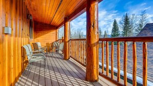 A wooden deck with chairs and a railing, overlooking a snowy landscape. - Mount Victoria Lodge #d 3 Bedroom Condo by RedAwning (Frisco)